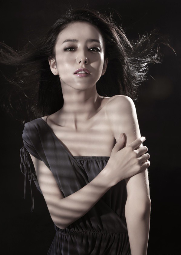 佟丽娅身穿黑色刺绣礼服倚靠窗边，光影勾勒精致侧颜，华美中透着一丝神秘