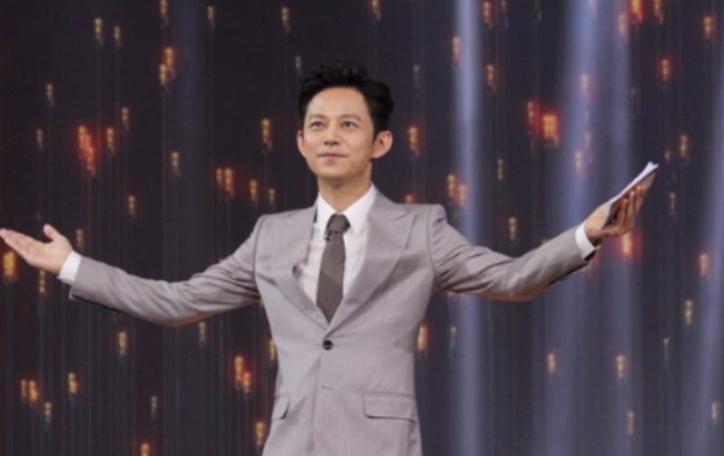 何炅主持大型晚会时的现场照片，手持话筒、笑容温暖